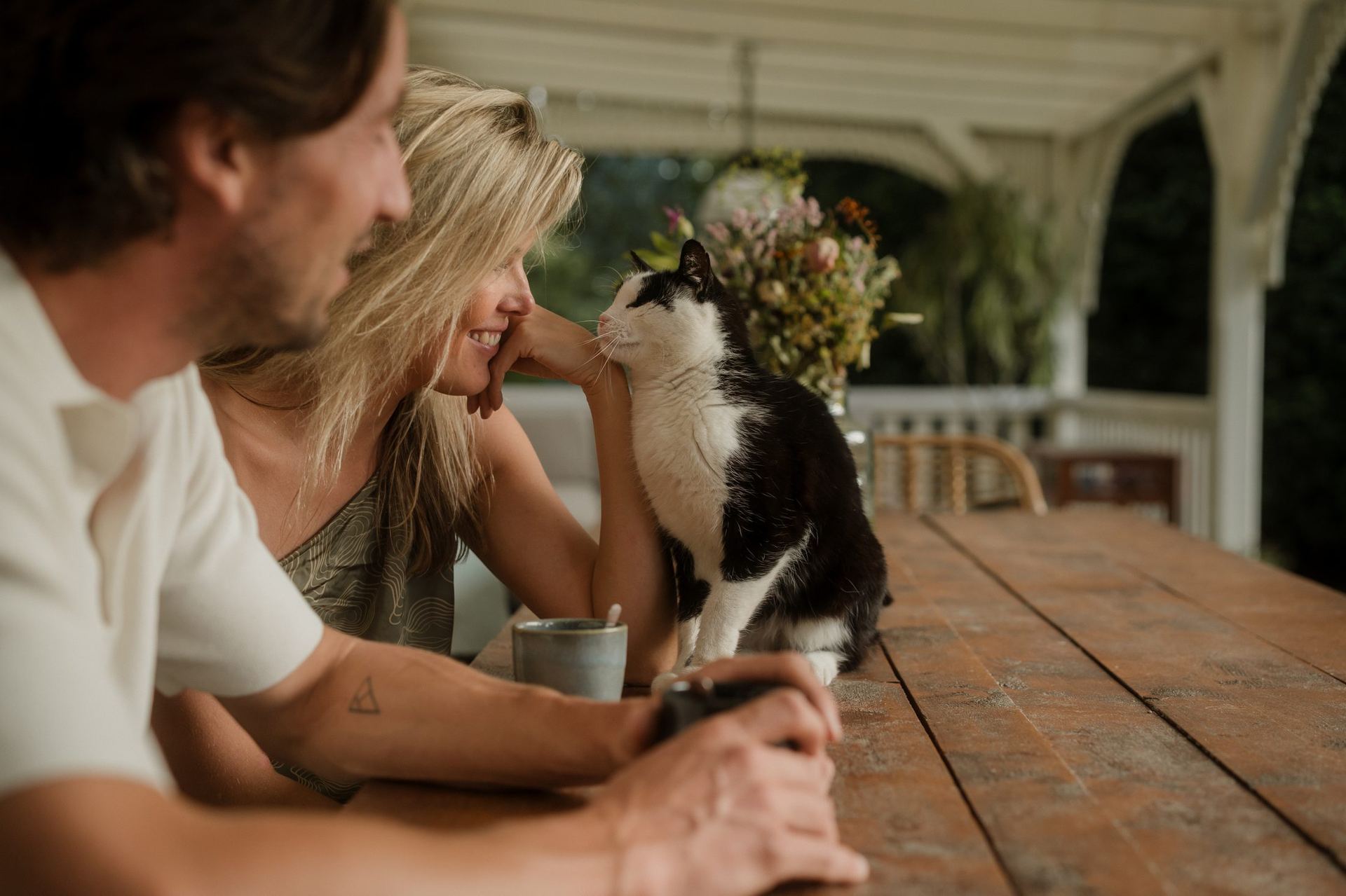 Couple with the stable cat at a wooden table on the estate of De Brennerhoeve