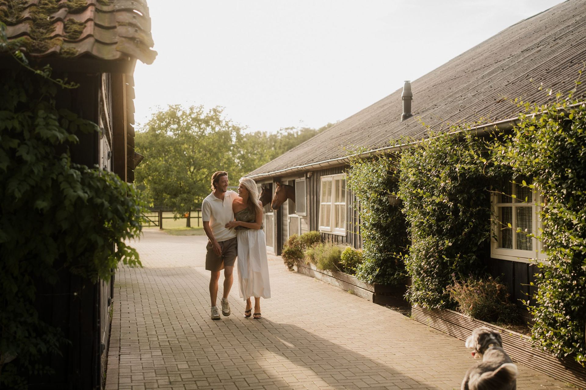 Couple walking past the stables with a dog