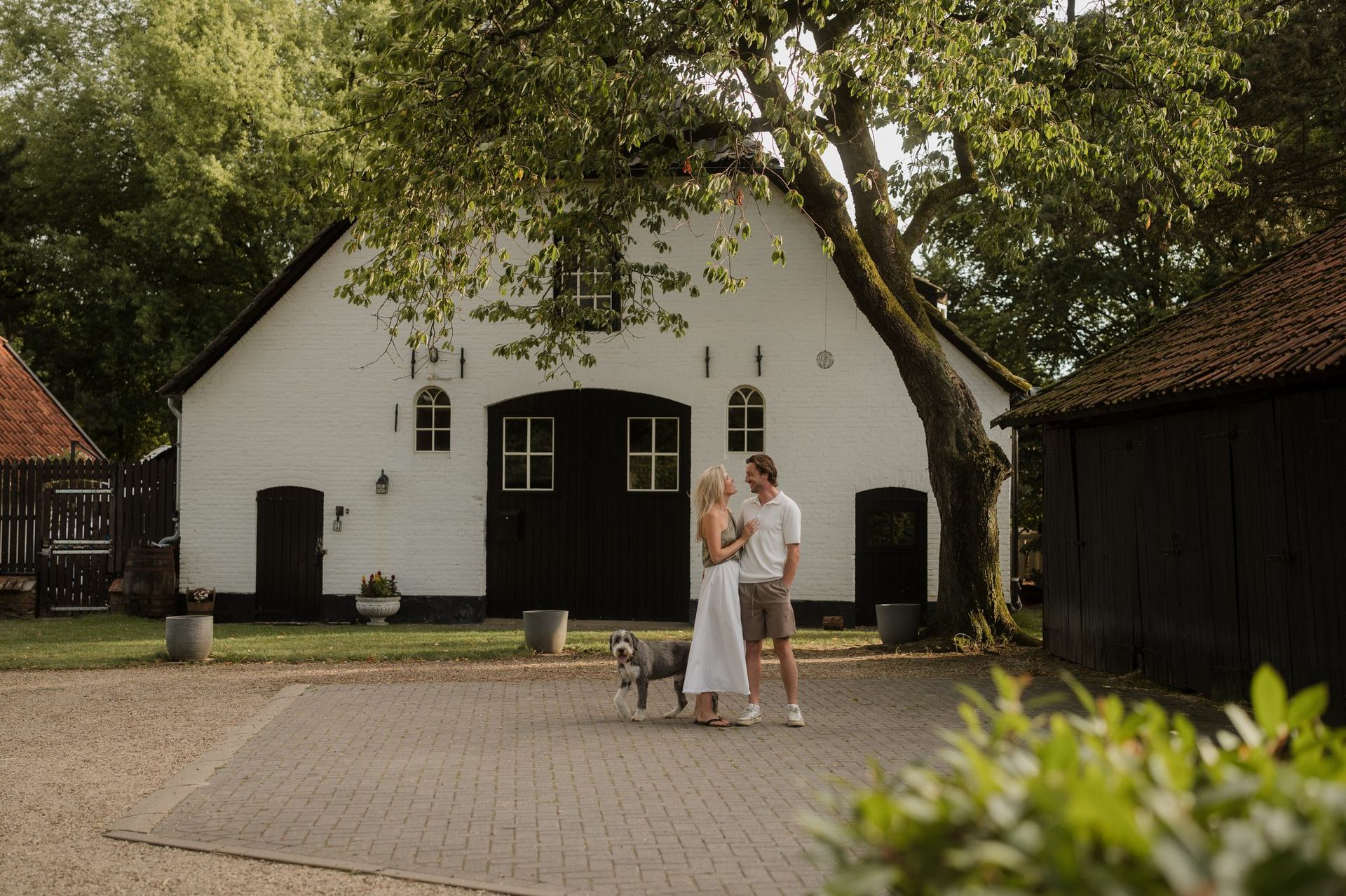 Daphne en Jurre bij de witte schuur van De Brennerhoeve, met hun hond